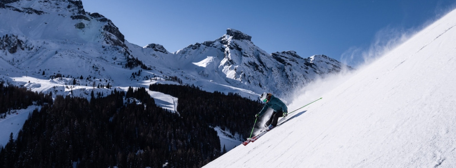 Skier on steep black piste in Arabba-Marmolada ski area with Dolomites in background
