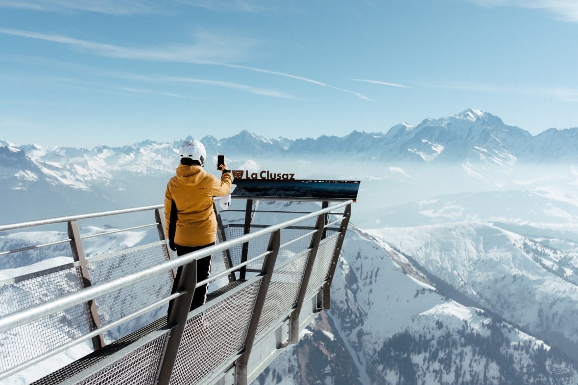 Skier on viewing platform above La Clusaz photographing the Aravis mountains