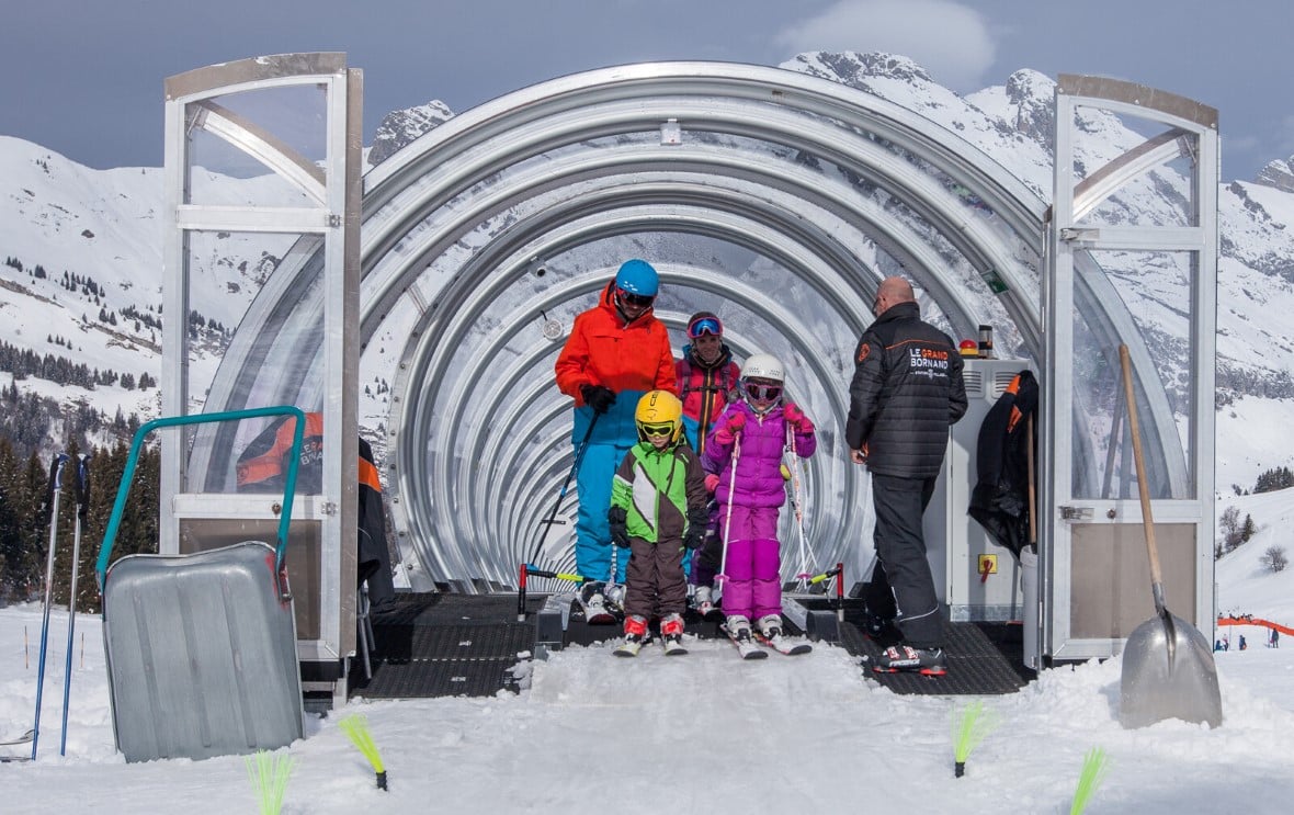 A family on skis emerges from a magic carpet tunnel in le Grand Bornand near La Clusaz