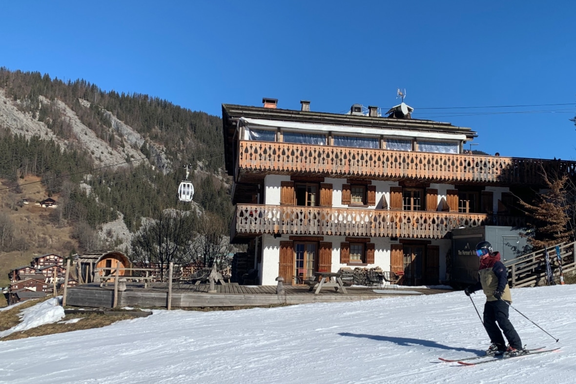 Skier in La Clusaz skiing past La Ferme Hotel and Mountain Restaurant