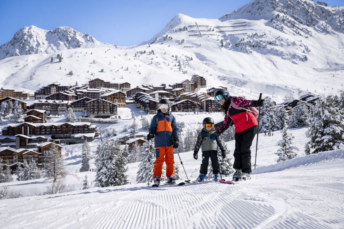 Family on skis on groomed slope in front of Belle Plagne in la Plagne