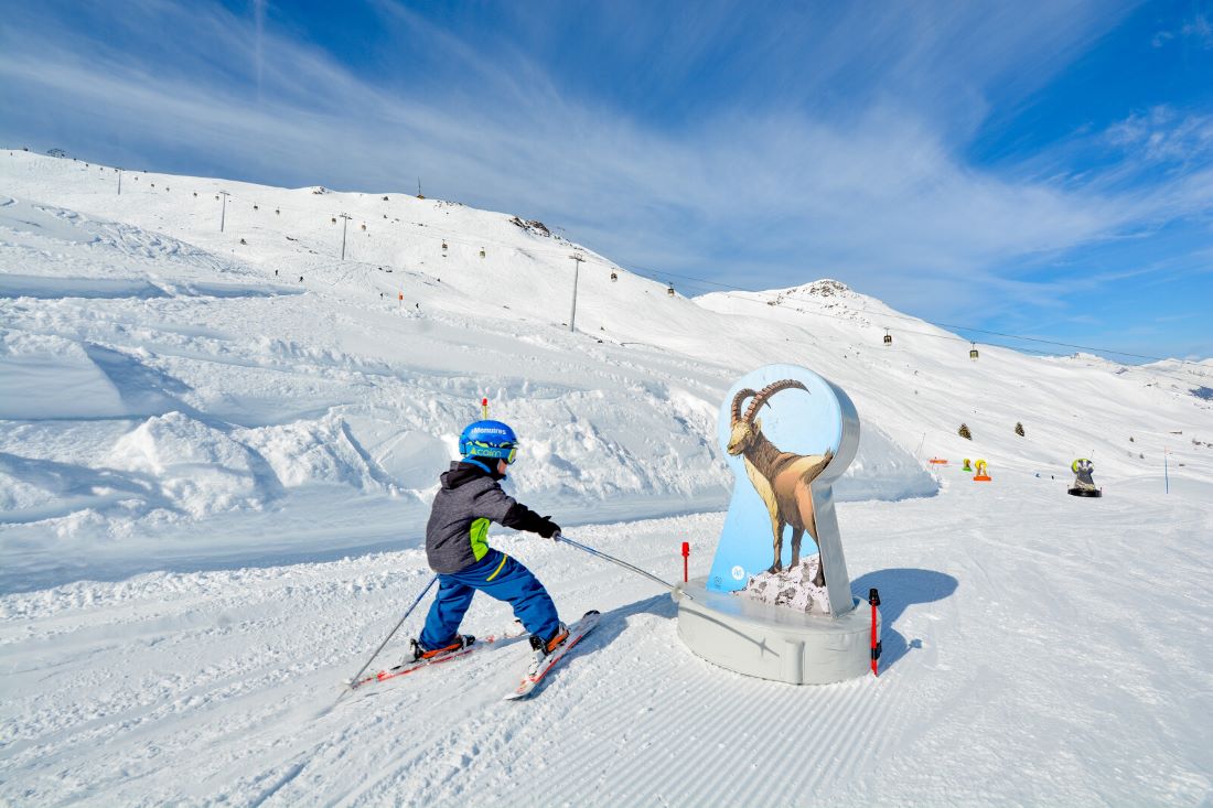 Small child skiing next to animal sculpture in Les Menuires