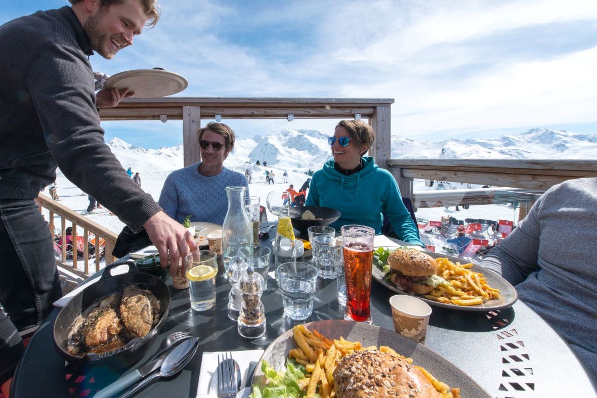 Friends eating lunch on terrace of mountain restaurant in Les Menuires