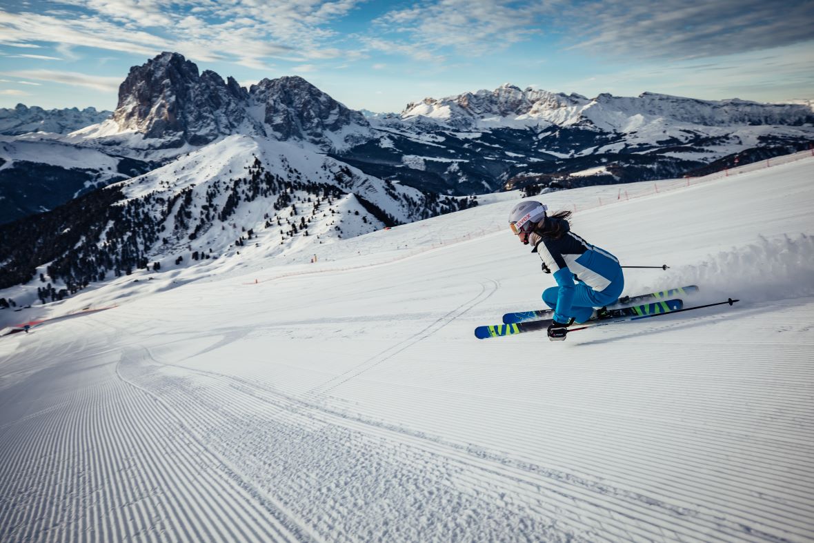 Skier descending Seceda mountain above Santa Cristina with Sassolungo in background