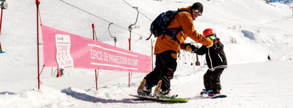 Instructor teaching young boy how to snowboard in a Tignes Ski School lesson