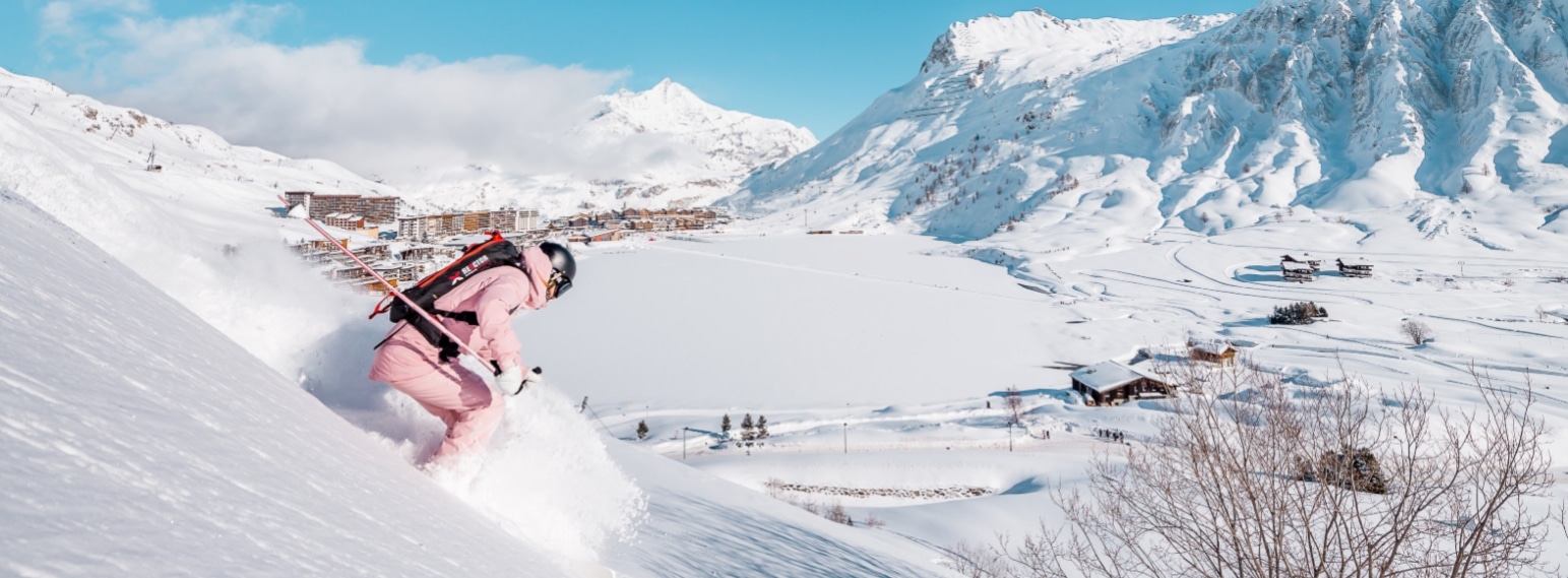 Freeride skier above Lac de Tignes with Tignes Le Lac ski resort in the background