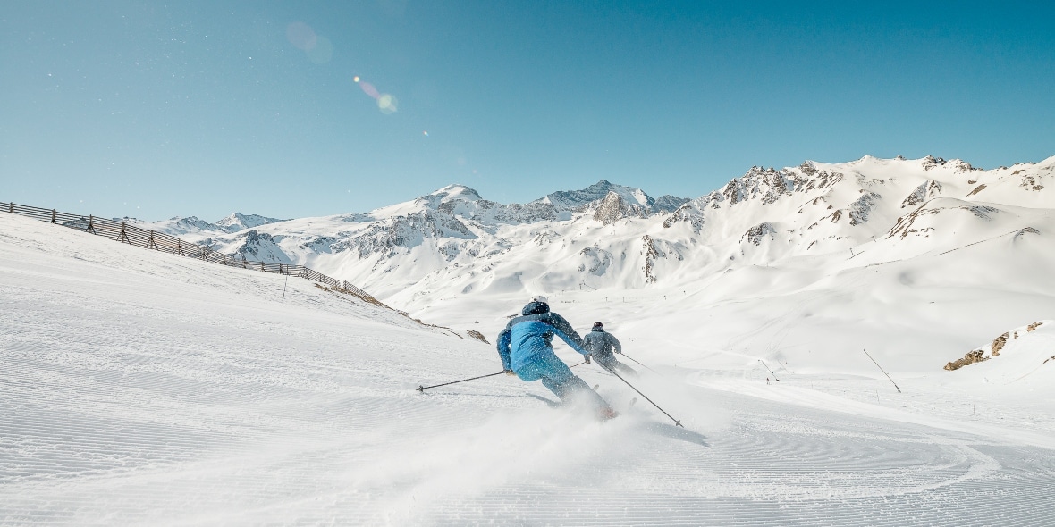Two skiers descending a gentle groomed ski slope in Tignes Ski Resort