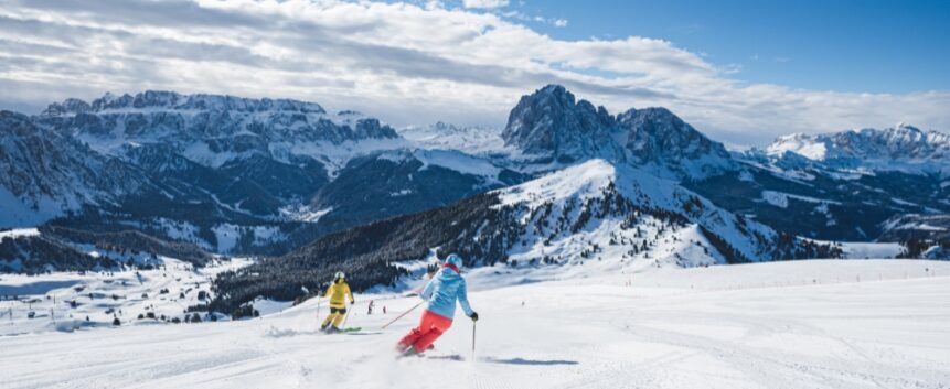 Skiers in Val Gardena on the Sella Ronda with Gruppo del Sella and Sassolungo in the background